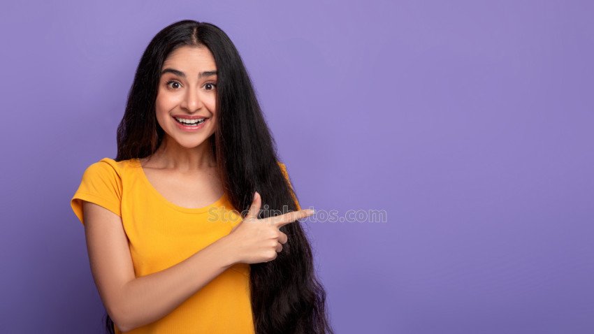 Excited indian woman pointing aside at copy space