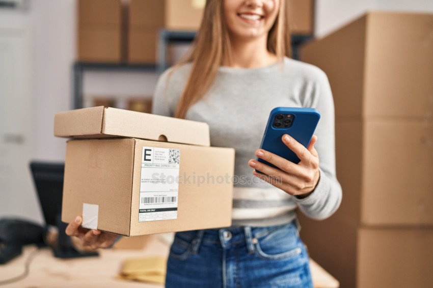 Young blonde woman ecommerce business worker using smartphone ho