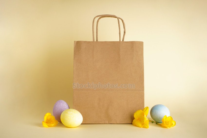 Easter eggs and paper bag on yellow background