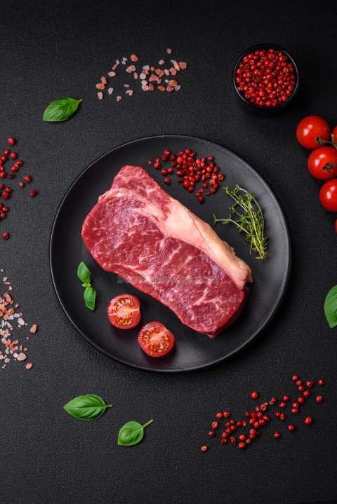 Fresh raw beef striploin steak with salt, spices and herbs