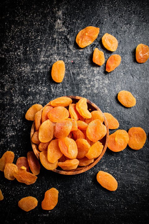 Delicious dried apricots in a wooden plate.